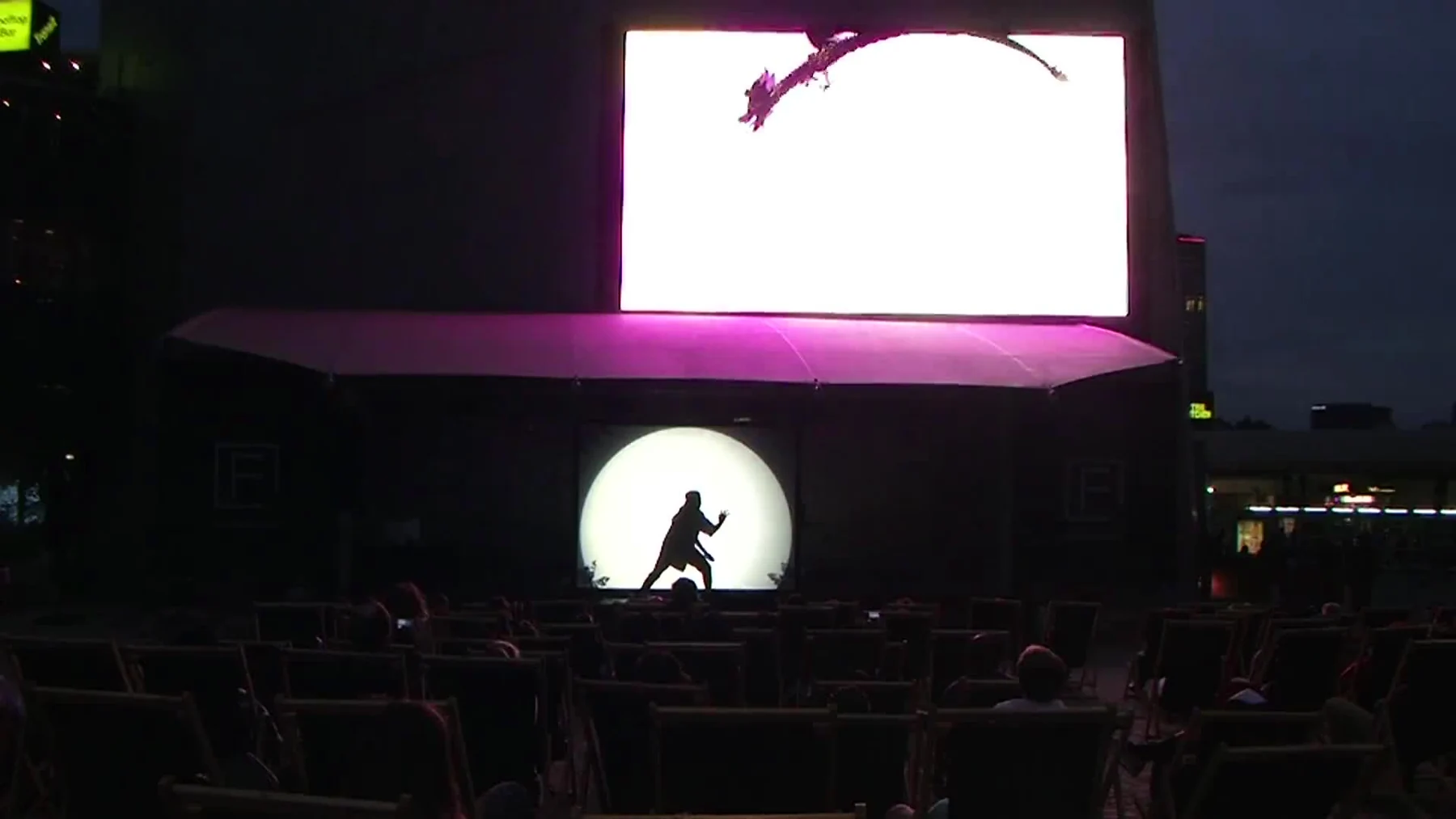A participant performs in silhouette beneath the Electric Dragon screen at Federation Square.