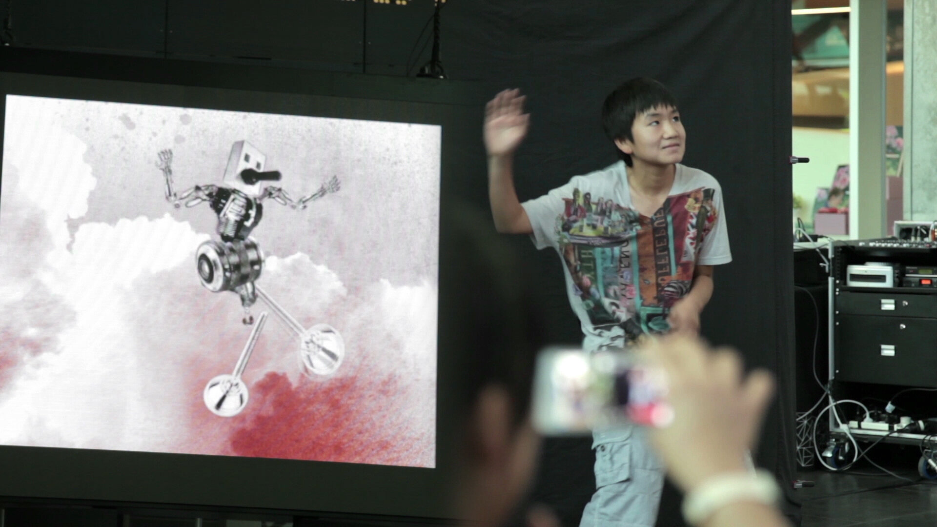 Participant gesturing beside a screen displaying a digitally animated character.
