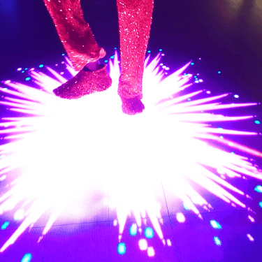 Close-up of a participant’s feet above a bright pink and white radial floor pattern.