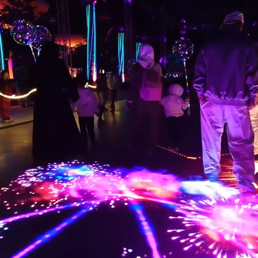 Visitor standing on a bright pink and purple interactive floor projection.