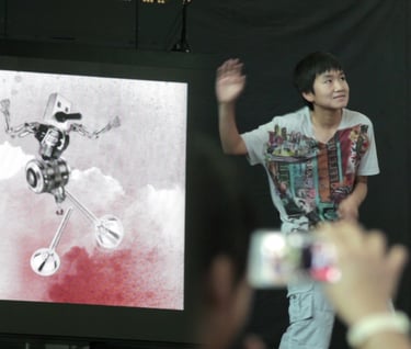 Participant gesturing beside a screen displaying a digitally animated character.