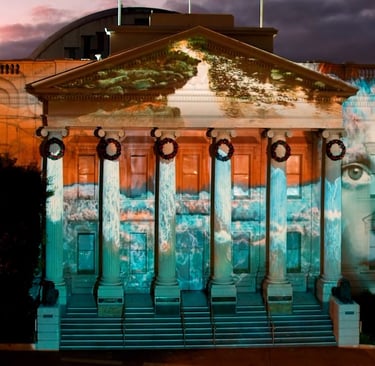 Projection mapping across a civic building’s columns and pediment at night.