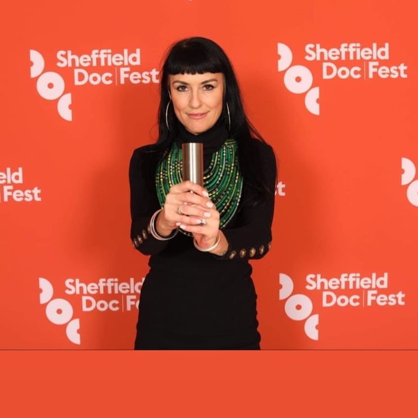 Georgie Pinn holding the Sheffield Doc/Fest award