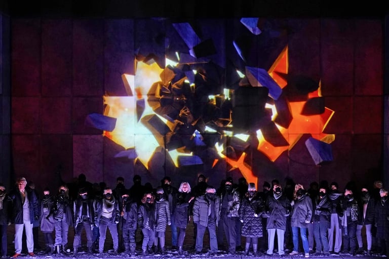 Performers on stage beneath angular purple, orange and white projections.